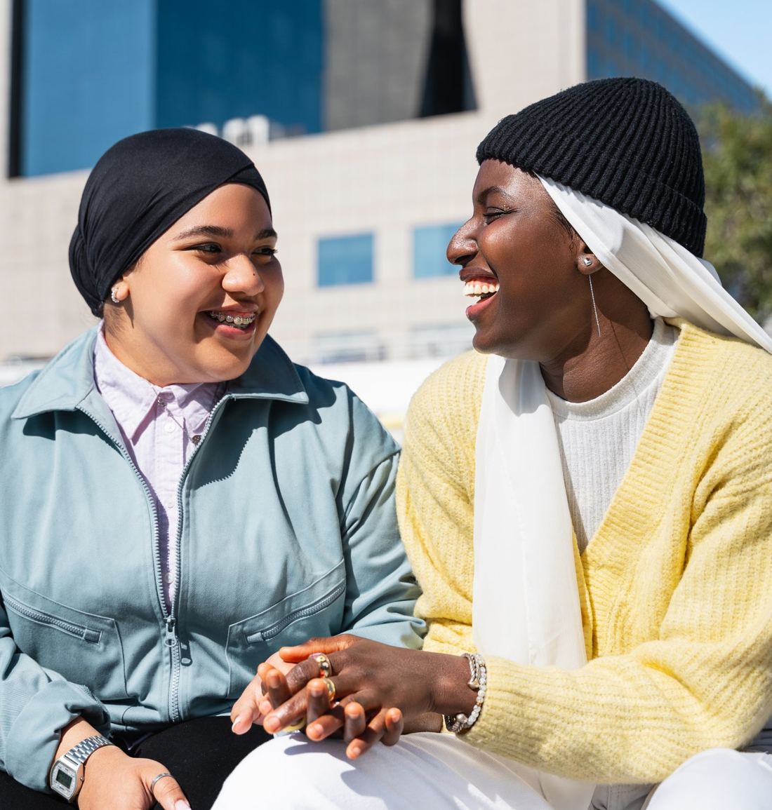 Two young women laughing together on a city bench