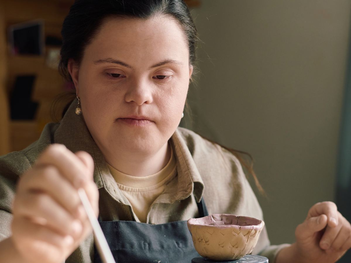 A woman painting a clay bowl at a table
