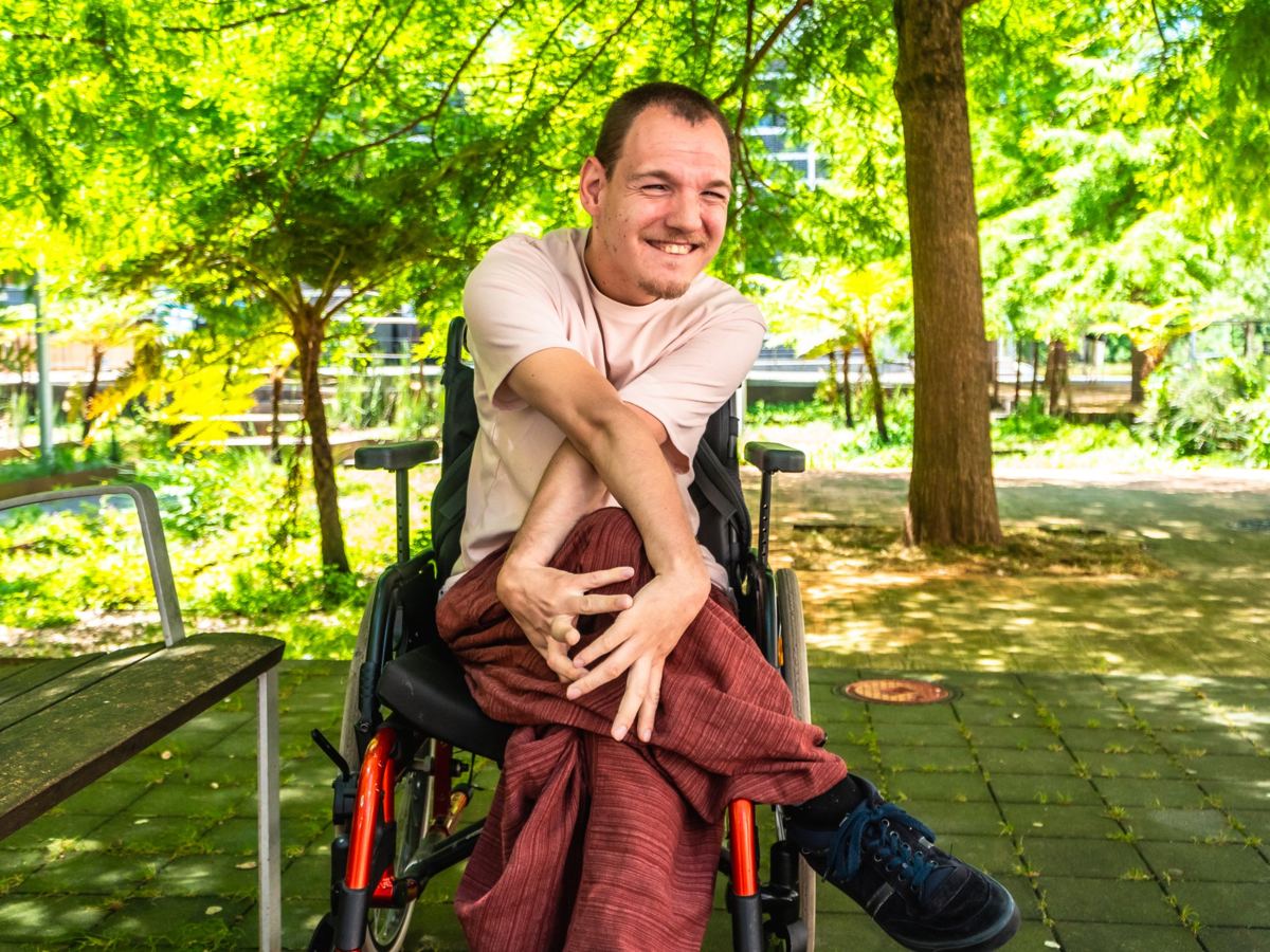 A man in a wheelchair laughing in a park